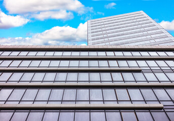 Fototapeta na wymiar A building made of glass and concrete against a blue cloudy sky.