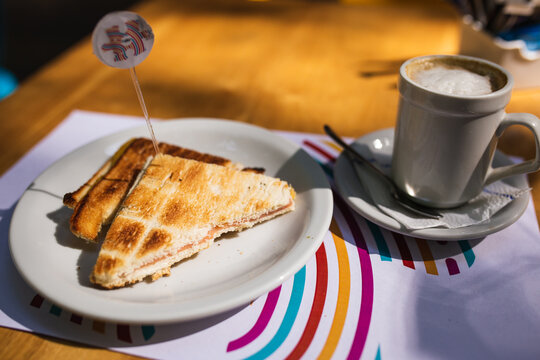 coffee next to toasted ham and cheese sandwiches - Powered by Adobe