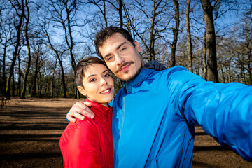 Young couple is taking a selfie in the woods. Portrait of a beautiful couple during a hike in the park.