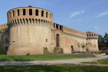 Sforza Castle in Imola, the main building with ravines sorrouded by circular bastions and a moat and a green lawn in front