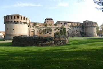 Sforza Castle in Imola, rear of the main building with ravines sorrouded by circular bastions and a green lawn with ruins in front