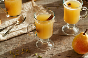 Hot pear drink on a wooden table with fresh pears and spices