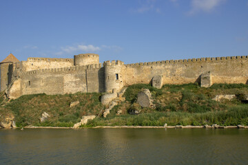 Obraz premium View of the defensive medieval fortress from the sea against the blue sky. Ancient citadel and towers of the fortress walls. Archaeological excavations of the historical bastion Akkerman.