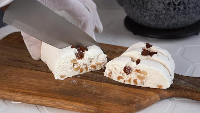 The chef cuts traditional eastern dessert halva sesame into slices with knife. 