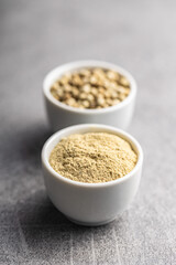 White ground pepper and whole peppercorn spice in bowl.