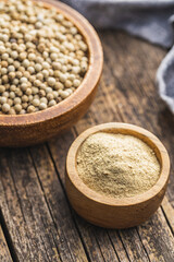 White ground pepper and whole peppercorn spice in bowl.