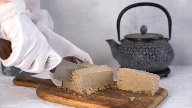The chef cuts traditional eastern dessert halva sesame into slices with knife. 