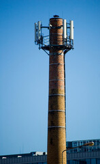 The top of a chimney with a cell phone antenna.