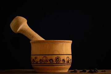 wooden mortar and pestle with spices on dark background