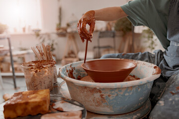 Skillful craftswoman making future ceramic bowl in art studio