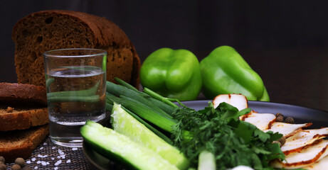 Salo. National Ukrainian product. A glass of vodka among vegetables and dark bread. Shallow depth of field	