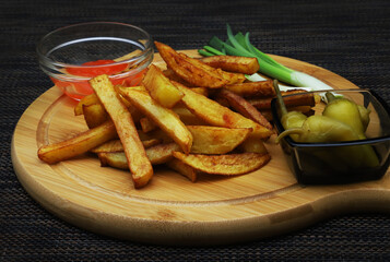 French fries on a serving board rimmed with containers of ketchup, green peppers and green onions