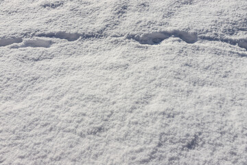 Beautiful winter background with snowy ground. Natural snow texture. Wind sculpted patterns on snow surface
