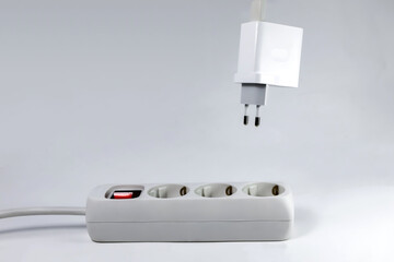 Power extension cord and AC power plug. Phone charger power adapter hanging above the power...
