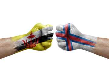 Two hands punch to each others on white background. Country flags painted fists, conflict crisis concept between brunei and faroe islands