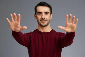 Naklejka premium handsome man stretches out his arms in front of him posing gesture with hands red sweater
