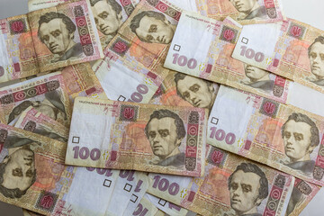 Ukrainian paper money is laid out on a blue background. 100 hryvnia banknotes