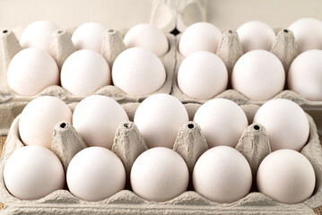 Blurred image of white eggs in cardboard trays.