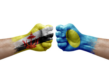Two hands punch to each others on white background. Country flags painted fists, conflict crisis concept between brunei and palau