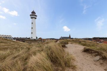 White lighthouse in the dunes in the small village of Egmond aan Zee in the Netherlands.