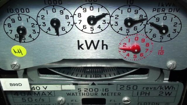 Close-up of a domestic electric meter showing the clock number dials and measuring disc rotating. Concept for energy, higher bills, price rise, meter reading, cost of living and tariffs.