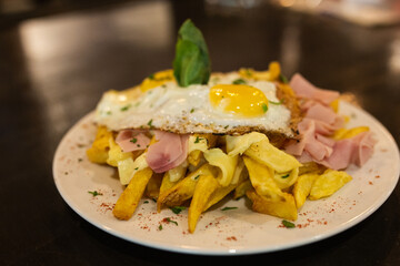 Fries with fried egg on a plate on a wooden table