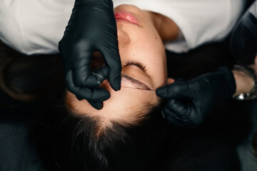 Beauty masters hands do permanent eyebrow makeup. Minimal trauma to skin. Eyebrow microblading is performed using manipulator handle and special nozzle with needles. Cosmetologist skill level - obrazy, fototapety, plakaty