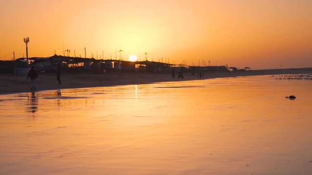 Beautiful view of Mandvi beach with orange sky during sunrise. Calm tropical beach background for summer vacation travel. At Mandvi, Kutch, Gujarat, India.