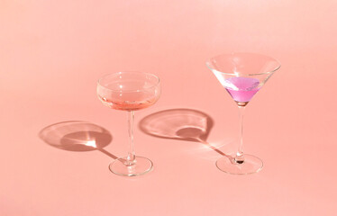 Concept on suny day with champagne and martini drink. Minimal layout glasses and shadow on pink...
