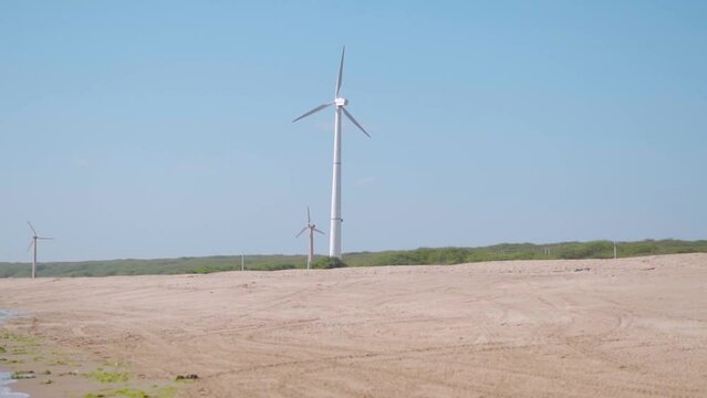 Windmills on the beach during the sunny day at Mandvi, Kutch, Gujarat, India. Concept of green energy and environment friendly electricity
