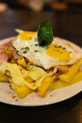 Fries with fried egg on a plate on a wooden table