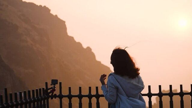 Young Indian woman watching sunrise at Girnar hills in Junagadh, Gujarat, India. Traveler enjoying view of sunrise after successful hiking to the summit. Travel and adventure concept