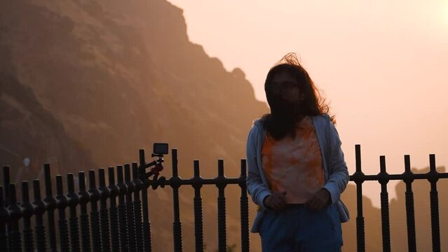 Young Indian woman watching sunrise at Girnar hills in Junagadh, Gujarat, India. Traveler enjoying view of sunrise after successful hiking to the summit. Travel and adventure concept