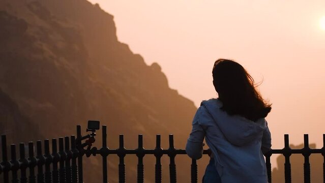 Young Indian woman watching sunrise at Girnar hills in Junagadh, Gujarat, India. Traveler enjoying view of sunrise after successful hiking to the summit. Travel and adventure concept