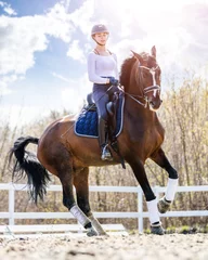Rolgordijnen Young teen rider girl riding horse at the field. © skumer