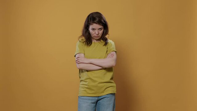 Serious woman entering room crossing arms feeling sad and disappointed looking grumpy and furious in studio. Bored young person feeling annoyed and stressed because of personal problems.