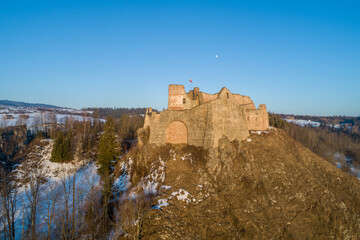 Fototapeta na wymiar Ruin of medieval castle in Czorsztyn, Poland built in 14th century. Aerial view in winter with the moon on blue sky