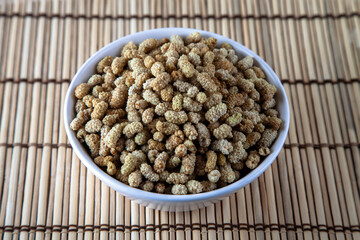 Dried mulberry in a bowl on wooden background