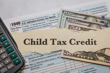 Child tax credit typed on paper with 1040 IRS form, calculator, and dollar bills