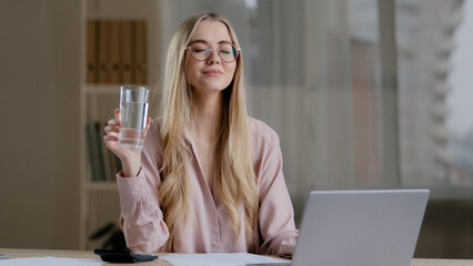 Caucasian busy business woman worker girl female student wearing glasses with laptop paperwork learning feeling thirsty drinking from glass water balance health care diet refreshment daily good habit