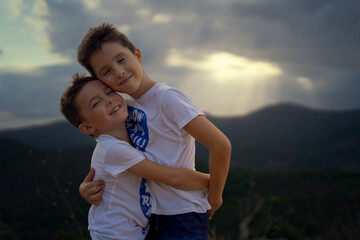 two brothers lovingly embracing each other with a summer sunset in the background