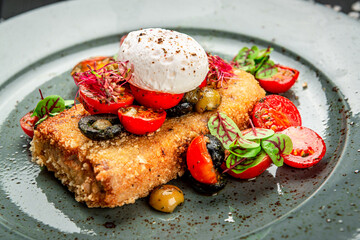 Wiener schnitzel with poached egg, olives and tomatoes.