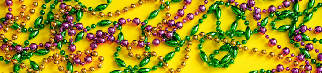 Mardi Gras concept. Multicolored beads on yellow background. Festive carnival symbols.