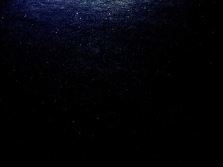 black background with blue sparkles, cosmos and falling stars in the sky concept, wallpaper texture, copy space 