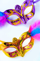 Two carnival masks with feathers and multi-colored beads on white background. Mardi Gras or Fat...