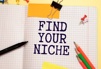 Text FIND YOUR NICHE on the short note with pencils on gray background