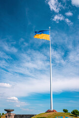 Ukrainian bicolor yellow blue national flagpole with trident emblem waving in wind against cloudy...
