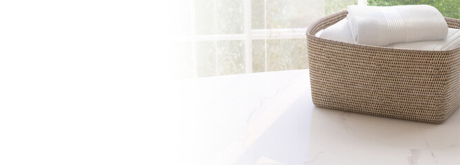 Natural brown open weave laundry basket with clean white towel on marble table top with warm beautiful morning sunlight from window by courtyard. 3D render for household product display background