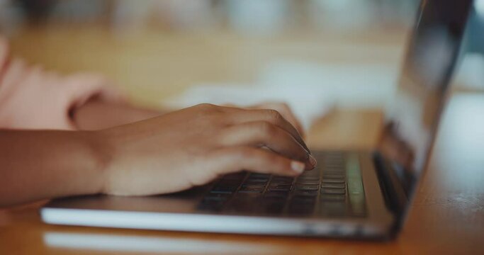 Black woman typing on keyboard on laptop in coffee shop