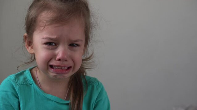 Portrait little girl sad upset child burst into tears cries sob looking at camera indoors. sincere children emotions feelings at home crying kid with pretty face. Concept childhood insult offend grief
